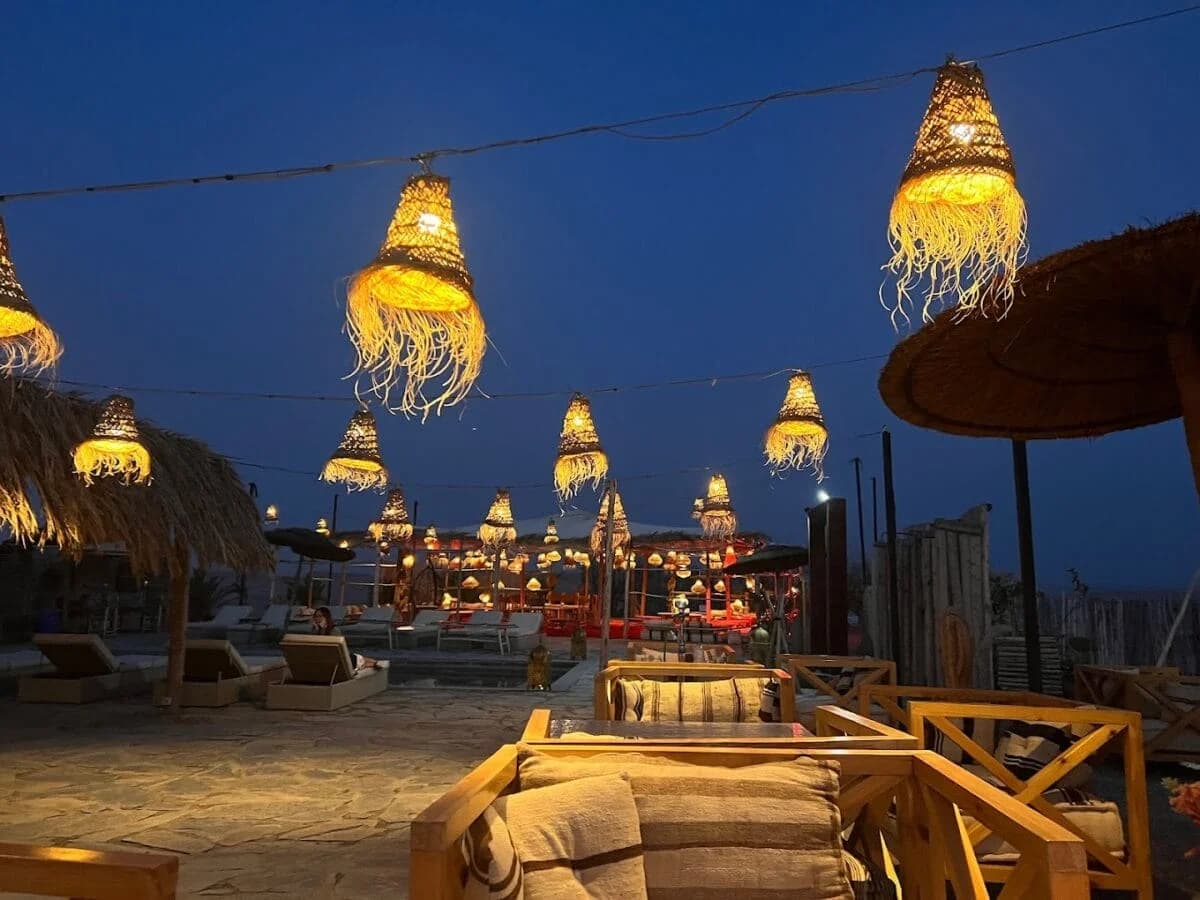 Desert dinner camp at dusk decorated with hanging woven lanterns