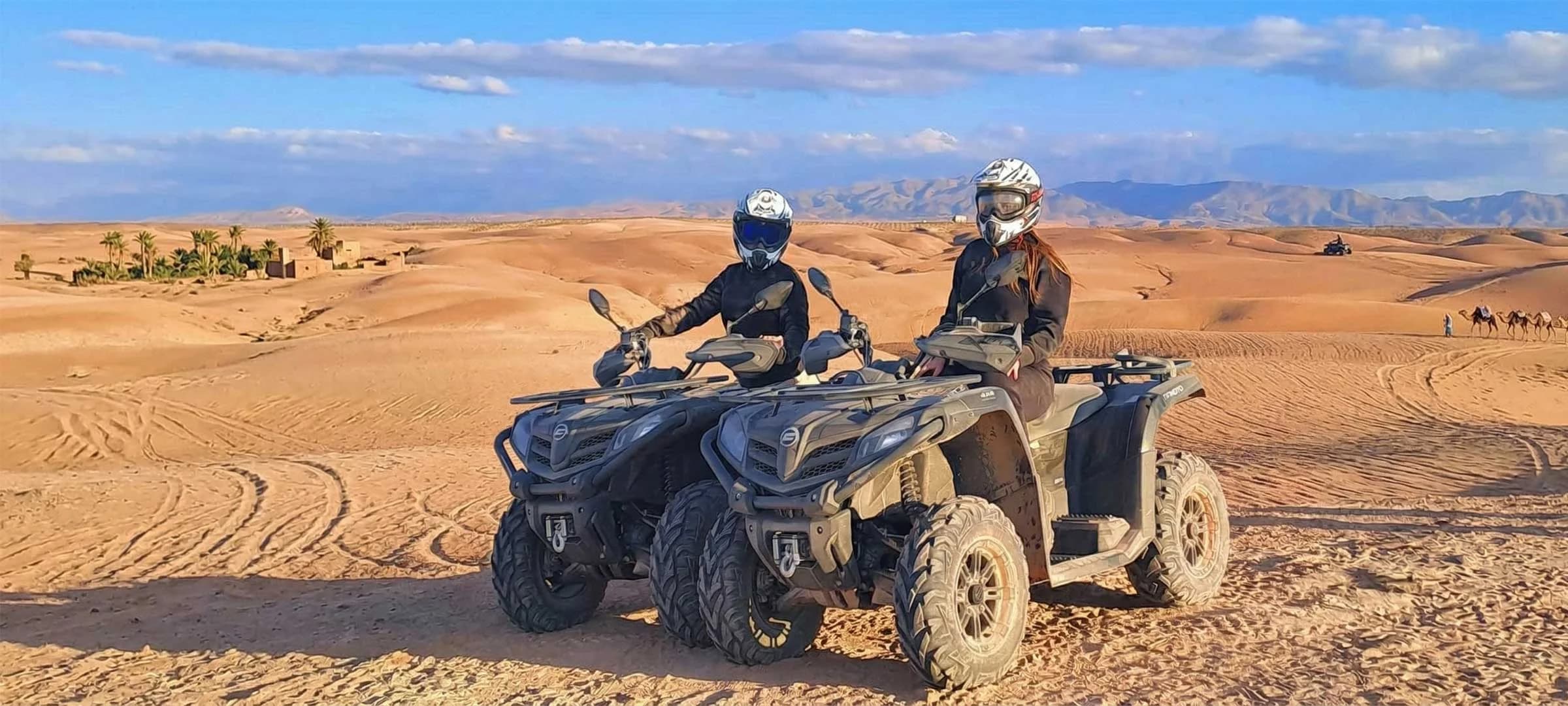 Riders standing with quad bikes on a dune ridge overlooking the wide Agafay Desert