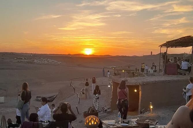 Guests silhouetted on a dinner terrace watching the sunset over the desert