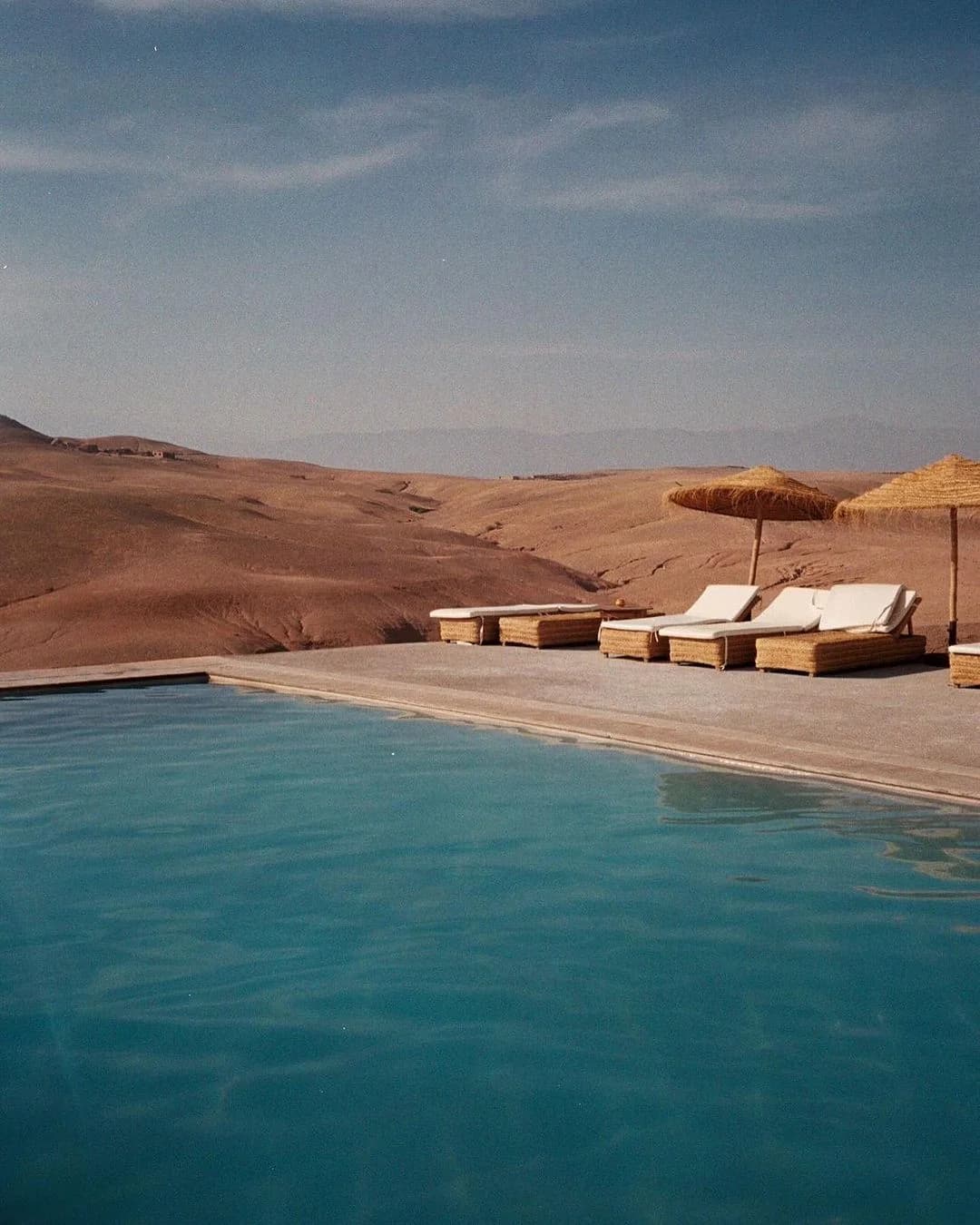 Infinity pool overlooking the desert dunes with sun loungers and straw umbrellas