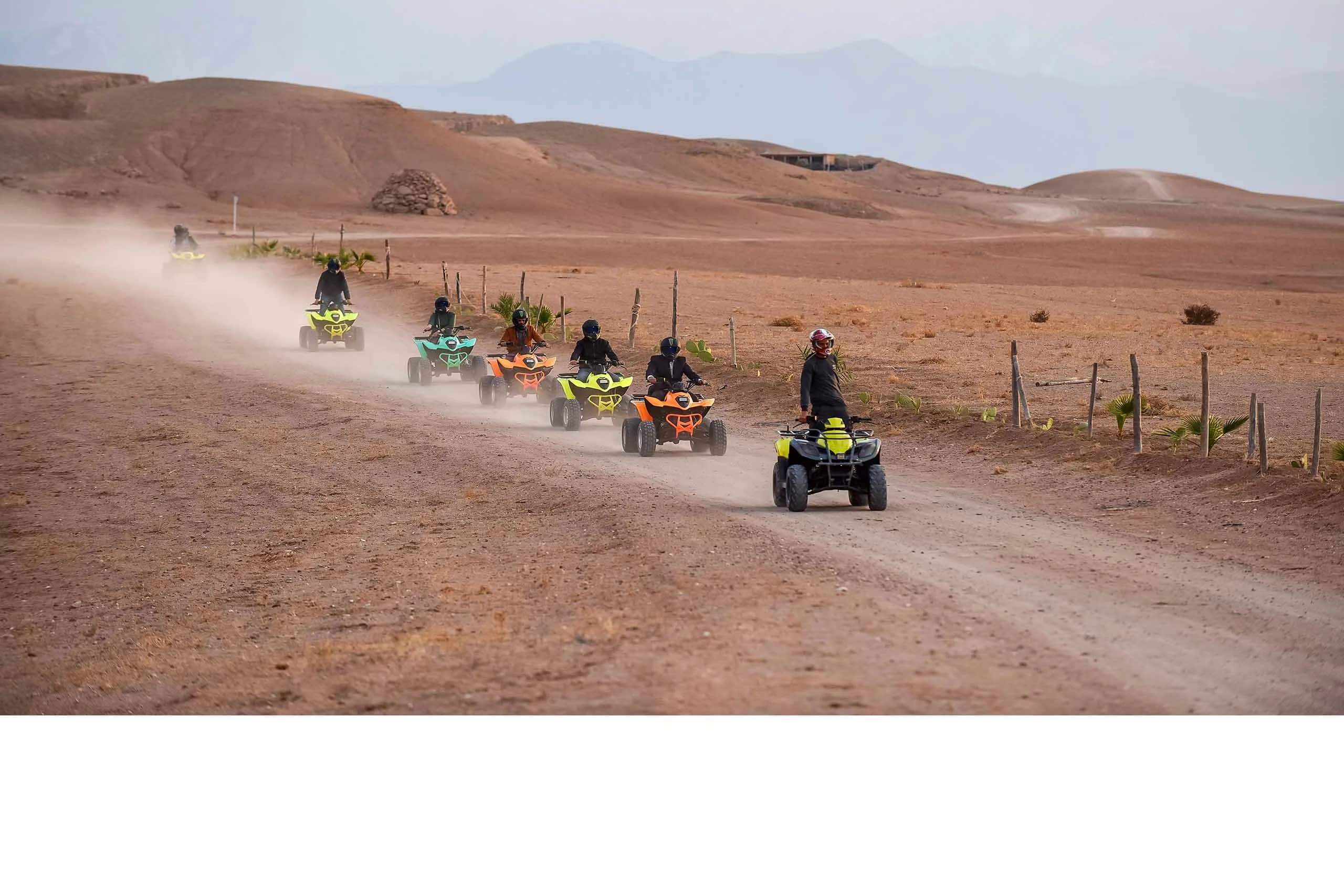 Quad bike riders driving across a stony desert landscape at dusk