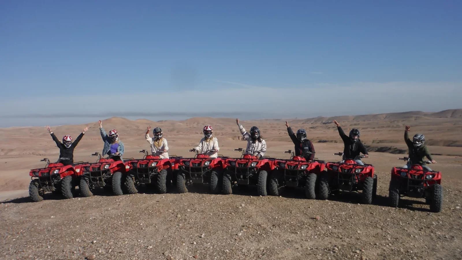Rider leading a convoy of quad bikes across a dusty desert bowl